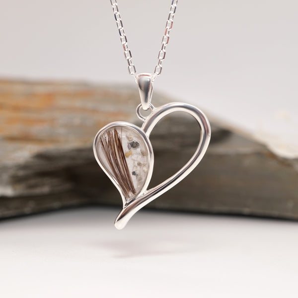 Silver memorial heart-shaped pendant with hair and ashes.